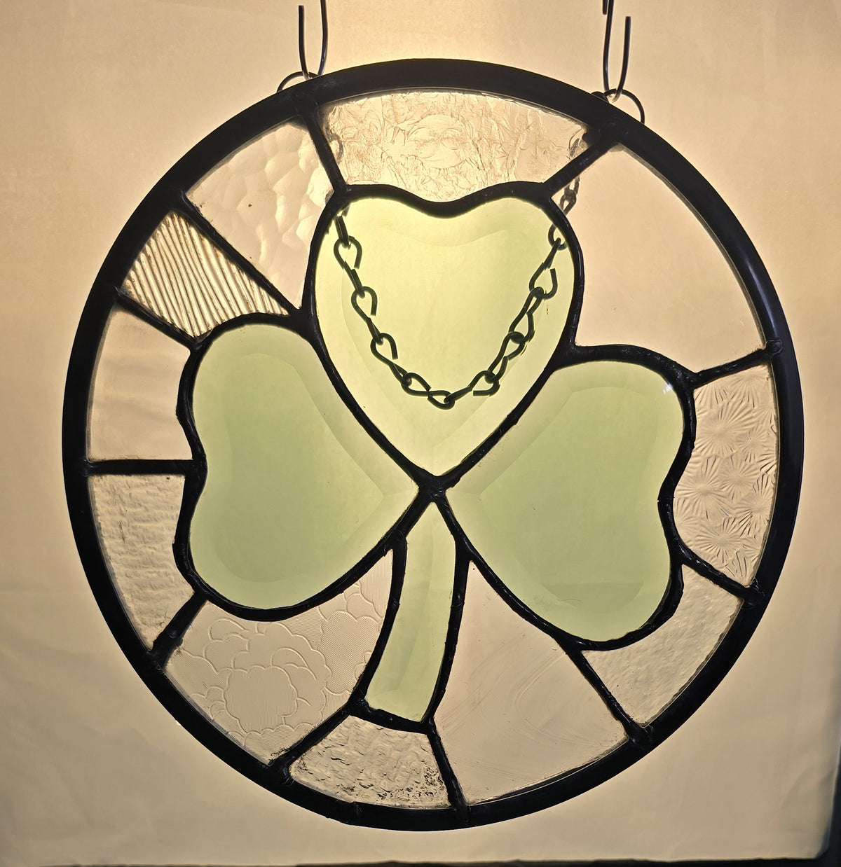 10-inch stained glass panel with a beveled glass green shamrock and a ring of clear textured glass pieces, handcrafted with black-patina zinc came.